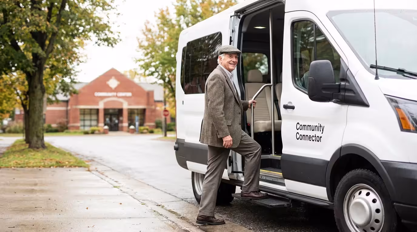 A smiling senior man confidently boarding a white community paratransit shuttle van.